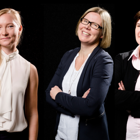 Three women stand against a black background