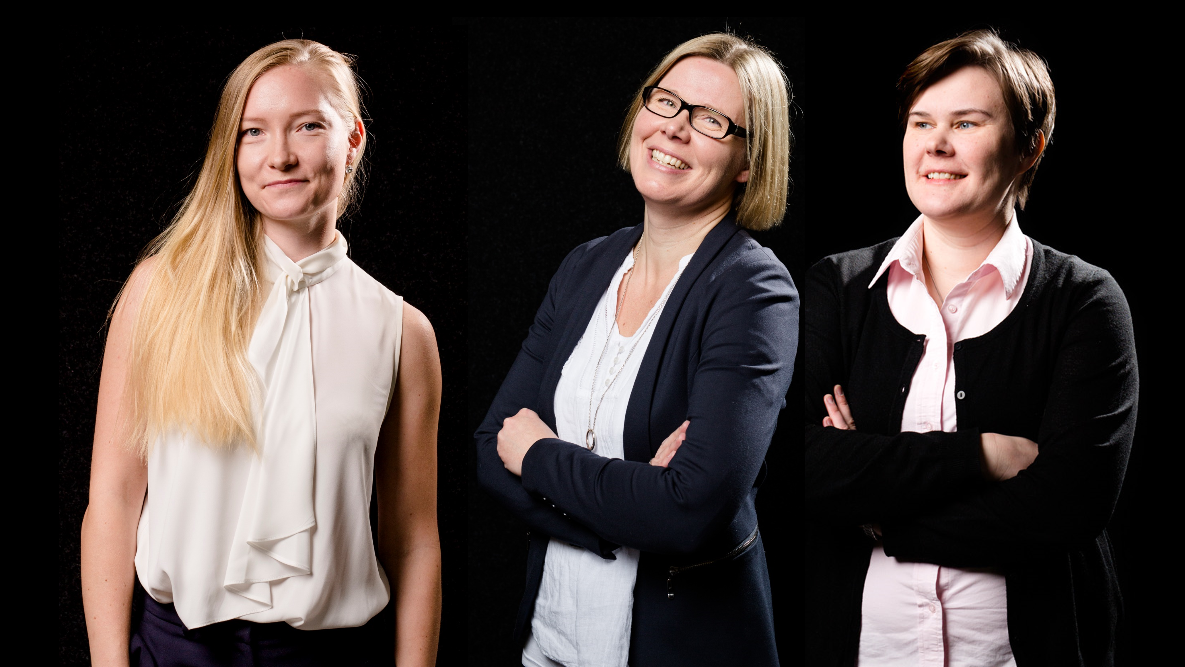 Three women stand against a black background